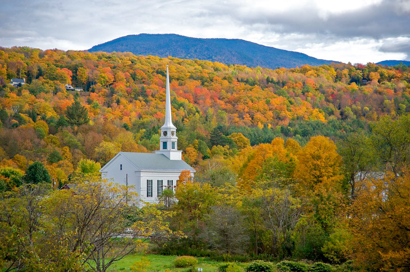 The Stowe Community Church surrounded by colorful trees in autumn