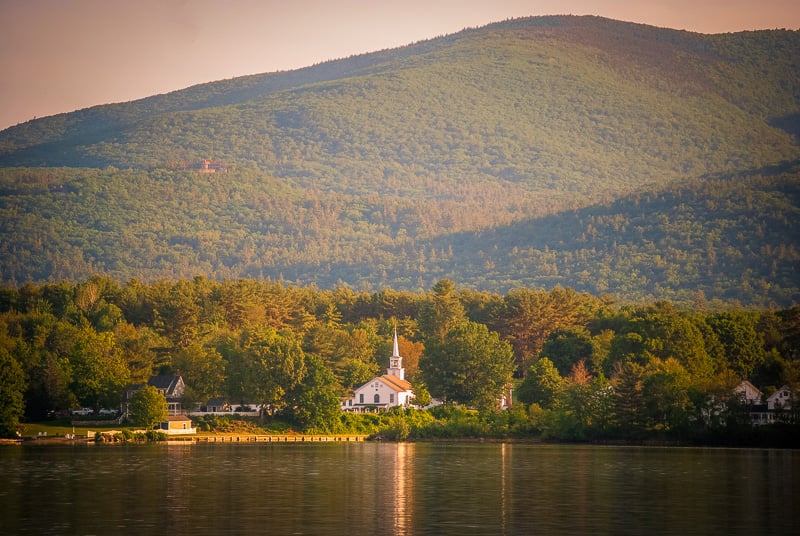 A serene church by a lake, embraced by lush trees