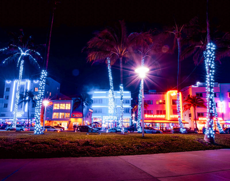Ocean Drive transforms into a bustling promenade at night, with neon lights and music filling the air.
