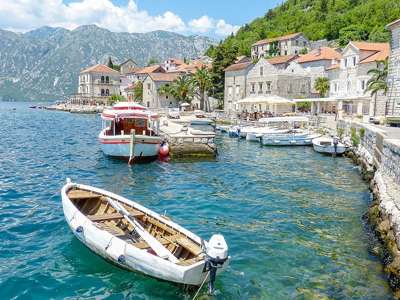 Boats docked near a mountain town, surrounded by serene waters and picturesque scenery