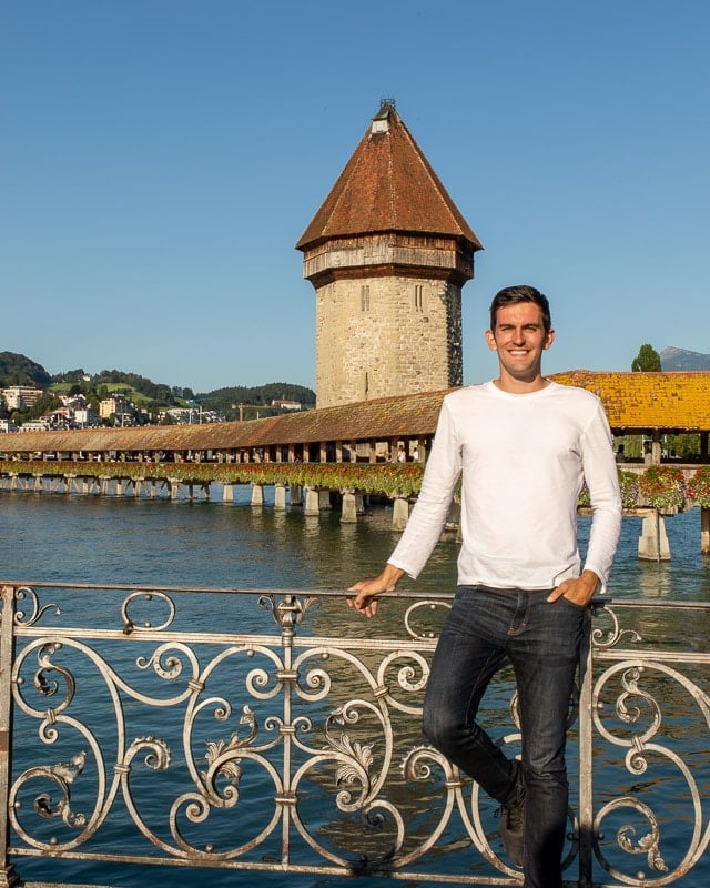 Jon standing on railing by river and tower