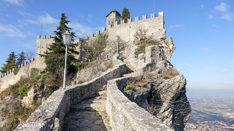 Scenic castle on mountain summit, staircase ascending to majestic fortress in San Marino