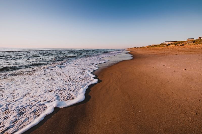 A stunning sunset over the calm waters of The Outer Banks, with vibrant orange and pink hues painting the sky