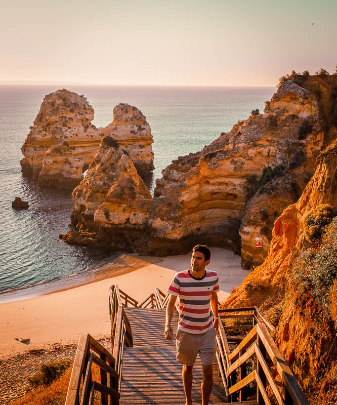 Jon walking on stairs leading to a sandy beach with ocean waves in the background