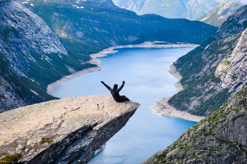 A person sitting on a mountain peak, gazing at a serene lake below